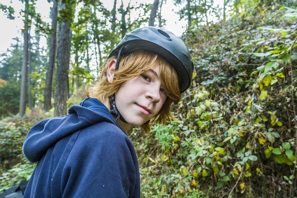 Ung tonårspojke i skogen med cykel hjälm — Stockfoto
