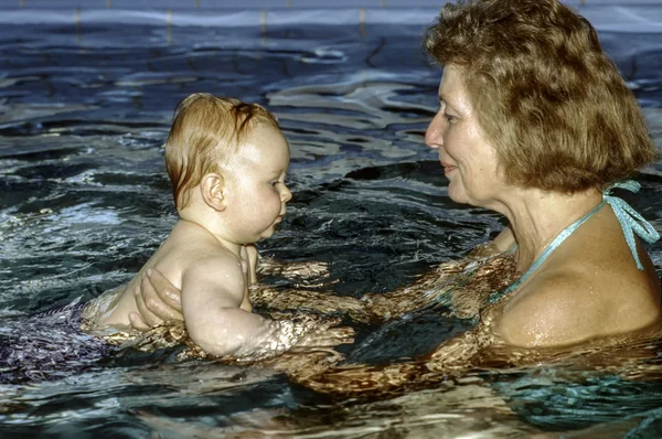 おばあちゃんと赤ちゃんは赤ちゃんを楽しむ水泳 — ストック写真