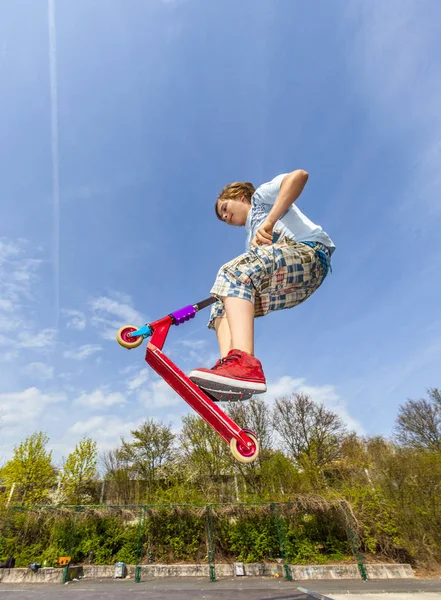 Chlapec je skákání s skútr přes páteř ve skate parku — Stock fotografie