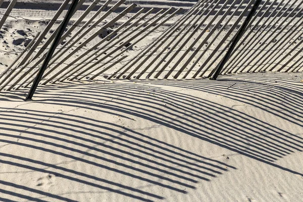 Fence at the beach gives a harmonic shadow — Stock Photo, Image