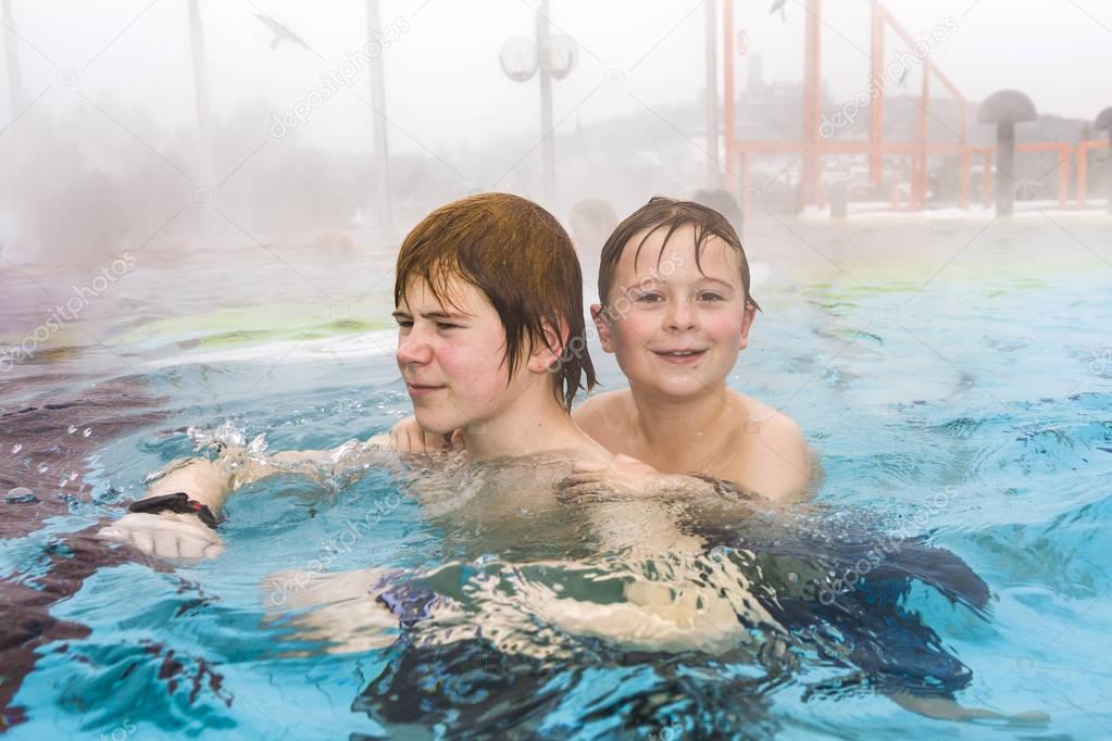 brothers are swimming in the outside area of a thermic pool in W
