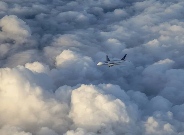 United Airlines avion vole dans les nuages sombres avec la lumière du soleil — Photo