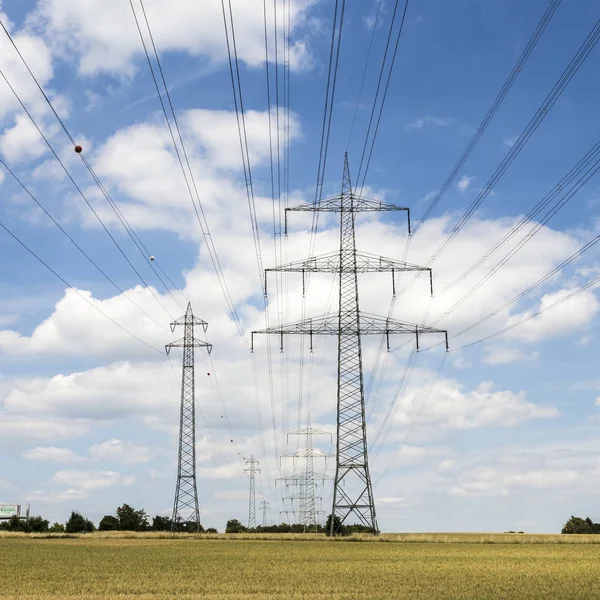 Pilone elettrico sul campo sotto il cielo blu — Foto Stock