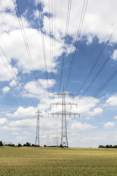 青空の下のフィールドに電気のパイロン — ストック写真