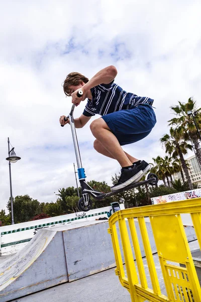 Menino gosta de saltar com seu empurrar scooter sobre um barriere — Fotografia de Stock