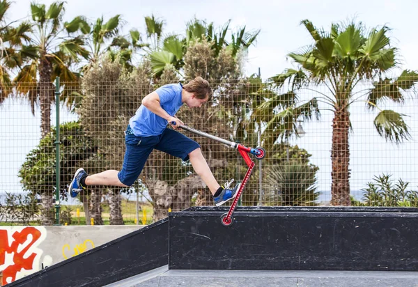 Menino monta sua scooter no parque de skate — Fotografia de Stock