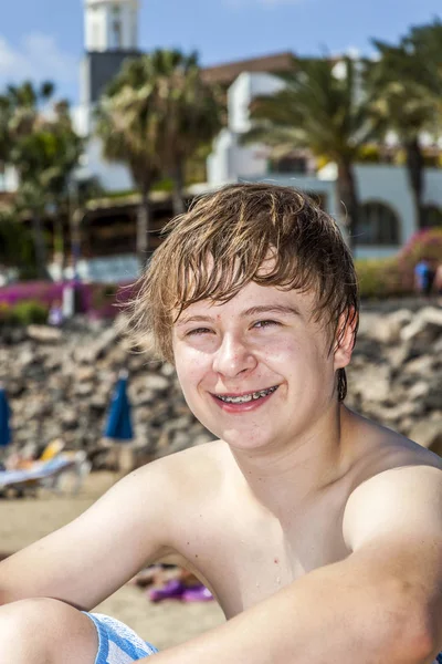 Menino feliz gosta de se sentar na praia — Fotografia de Stock