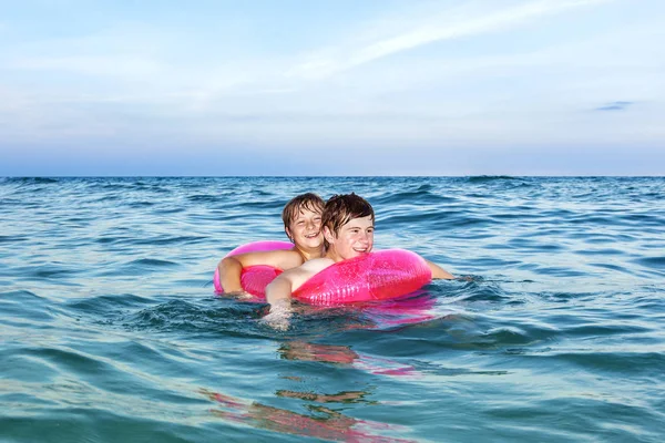 Irmãos em um ringue de natação se divertir no oceano — Fotografia de Stock