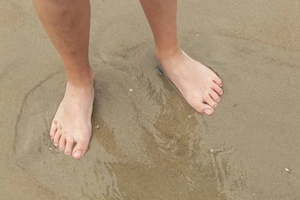 Ноги хлопчика на піщаному пляжі — стокове фото