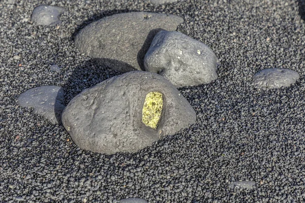 Оливиновый драгоценный камень, также называемый перидотом на вулканическом пляже — стоковое фото