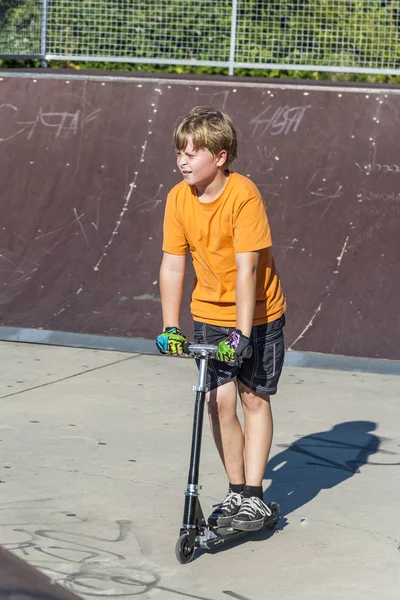 Boy has fun riding push scooter at the skate park — Stock Photo, Image