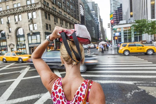 Vrouw oversteken van de straat met een zak zoals regen protectio — Stockfoto