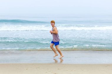 Çocuk sahilde koşu sahiptir