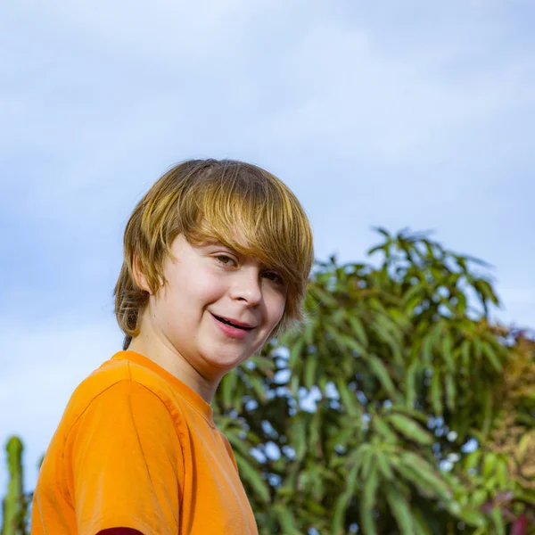 Glücklicher Junge lächelt unter blauem Himmel — Stockfoto