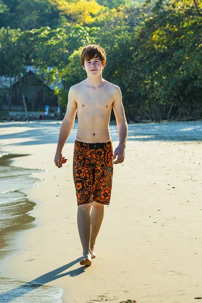 Jonge jongen wandelen langs het strand — Stockfoto