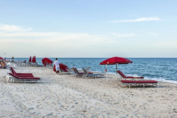 Hoteljunge sammelt am Ende die roten Liegen am Südstrand ein — Stockfoto