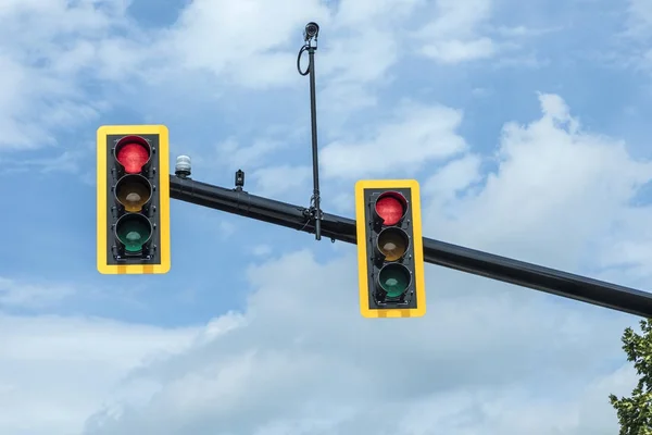 Rood verkeerslicht op hangende lamp onder hemel — Stockfoto