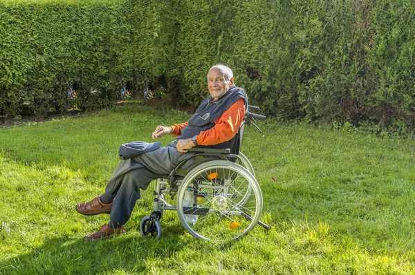 Uśmiechający się zadowolony starszy mężczyzna siedzi w swoim ogrodzie — Zdjęcie stockowe
