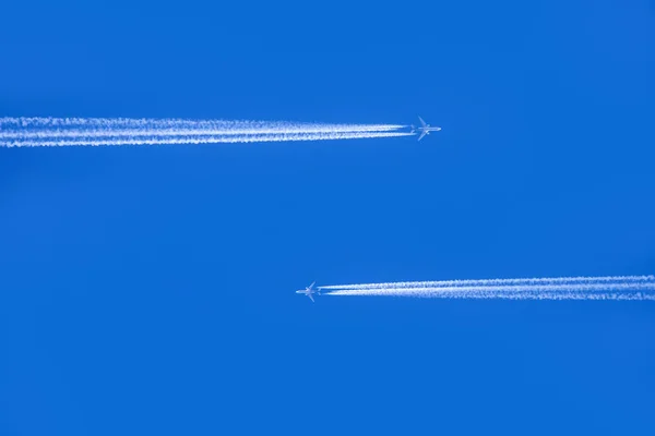 Блакитне небо з конденсаційною стежкою двох літаків, що проходять кожен о — стокове фото