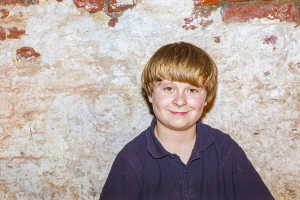 Niedlicher kleiner Junge mit altem Backsteinmauerhintergrund — Stockfoto