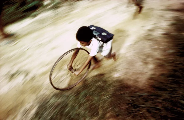 Çocuk okula giderken bisiklet tekeriyle oynuyor. — Stok fotoğraf