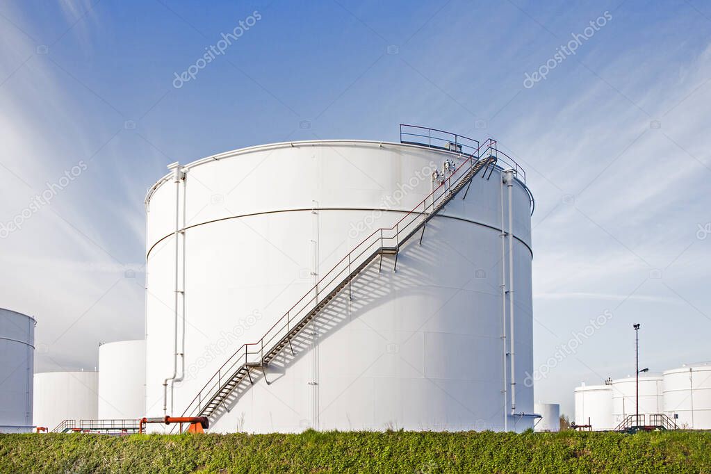 white tanks for petrol and oil in tank farm with blue sky