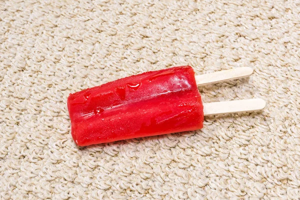 Röd Popsicle smälter på mattan — Stockfoto