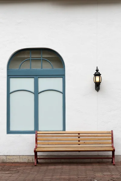 Открытая скамейка с белой стеной — стоковое фото