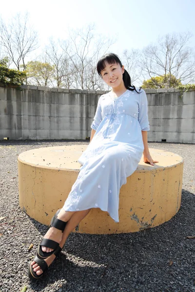 Νέοι ιαπωνική γυναίκα που κάθεται σε ένα παγκάκι — Φωτογραφία Αρχείου