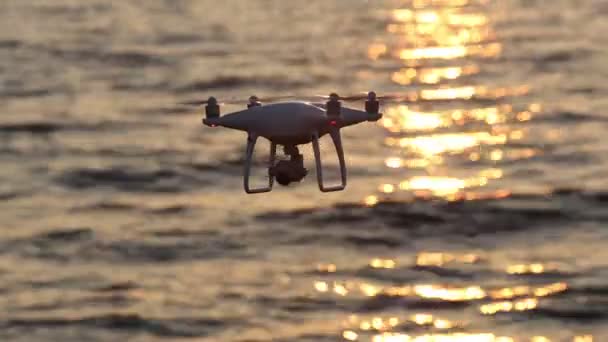 Remote controlled drone flying sparkle sunlight on sea — Stock Video