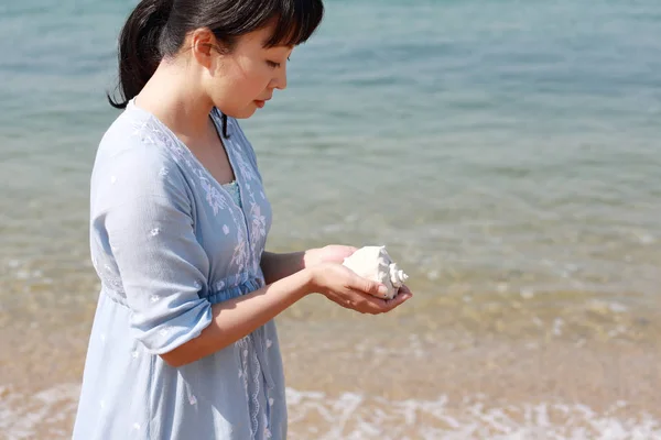 Joven japonés mujer mano celebración un concha de mar — Foto de Stock