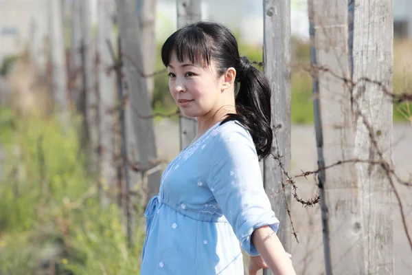 Ung kvinna står vid ett barbwire staket — Stockfoto