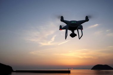 Yüksek çözünürlüklü video kamera deniz günbatımı gökyüzü karşı uçan ile donatılmış dron uzaktan kumandalı