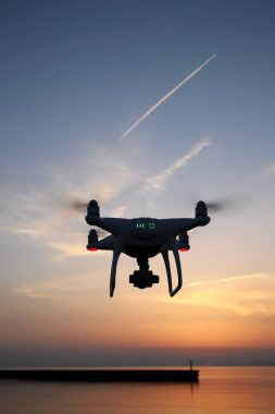 Yüksek çözünürlüklü video kamera deniz günbatımı gökyüzü karşı uçan ile donatılmış dron uzaktan kumandalı