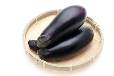 Arka planda bambu sepeti üzerinde Japon taze patlıcanları.