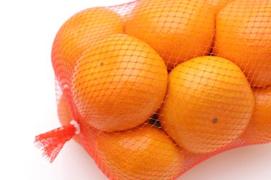 Beyaz arka planda plastik poşette Japon narenciye meyvesi.   