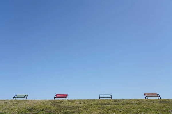 草の丘の上のベンチ青い空と緑の草 — ストック写真