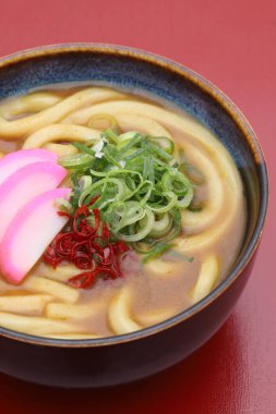 Japon körili udon şehriyelerini kırmızı masada bir kaseye koy.