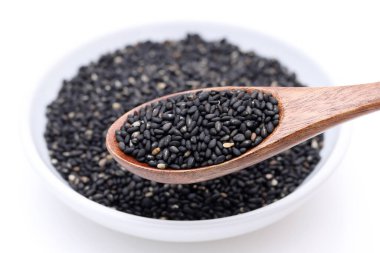 Tahta kaşıklı siyah susam tohumları. Beyaz arkaplanda susam tohumları 