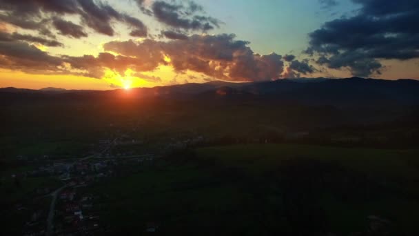 Colinas verdes e vila rural por do sol, câmera subindo — Vídeo de Stock