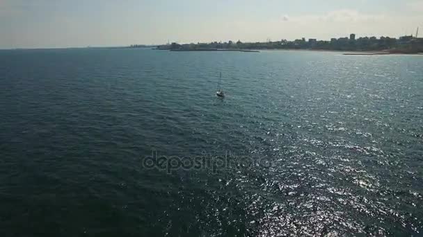 Vuelo aéreo sobre velero en el mar negro con Costa de la ciudad en el fondo — Vídeo de stock