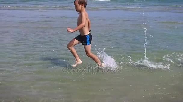 Niño corriendo en el agua en el mar, cámara lenta — Vídeo de stock