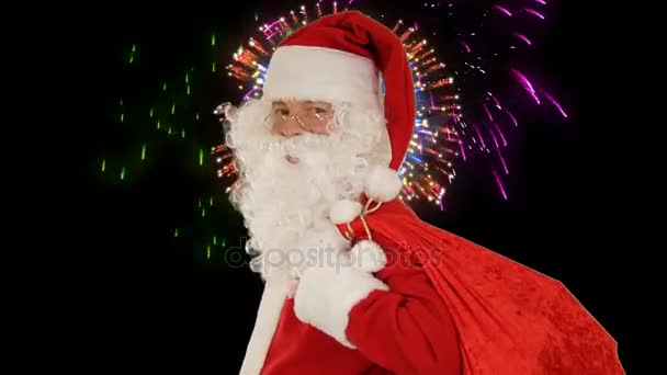 Santa Claus seine Tragetasche, schaut die Kamera sendet ein Kis und Welle, Feuerwerk — Stockvideo