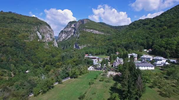 Аэрофотоснимок Polovragi монастырь, в окружении зеленых холмов, Румыния, панорамирование — стоковое видео