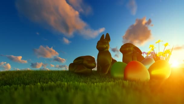 Huevos de Pascua y conejos de Chocolate en prado verde contra hermoso amanecer — Vídeos de Stock