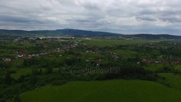 Aerial Flug über grünen Waldhügel mit Stadt im Hintergrund — Stockvideo