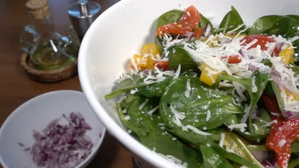 Parmezaanse kaas vallen op een spinazie salade met paprika en tomaten, slow-motion bij 250 fps — Stockvideo