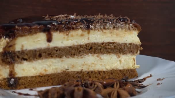 Kawałek czekolady ciasta na talerzu przeciwko drewno, obrotowy, 4k — Wideo stockowe