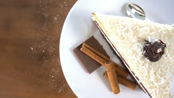 Φέτα άσπρο κέικ σοκολάτας σε ένα πιάτο περιστρεφόμενη, σωματίδια που φέρουν — Αρχείο Βίντεο