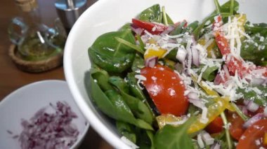 Bir ıspanak salatası dolmalık biber ve domates, ağır çekim 500 fps düşüyor Parmesan peyniri